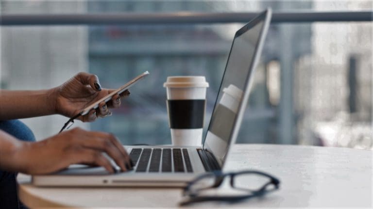 woman using laptop and holding mobile phone